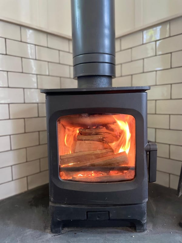 Modern cast-iron wood-burning stove with glowing fire in a boutique holiday cabin interior.
