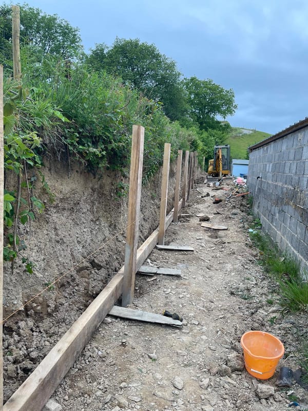 Completed bespoke oak sleeper retaining wall with freshly laid organic mulch prior to planting.